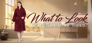 A woman wearing a plush burgundy bathrobe stands in a softly lit bathroom interior, with large overlaid text reading 'What to Look for in a Bathrobe for Women?' and a small 'Creava' logo in the top right.
