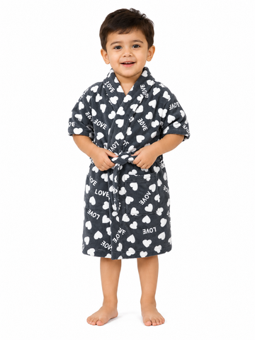 A young child wearing a dark gray plush bathrobe with a white heart and 'LOVE' print, standing against a solid white background.