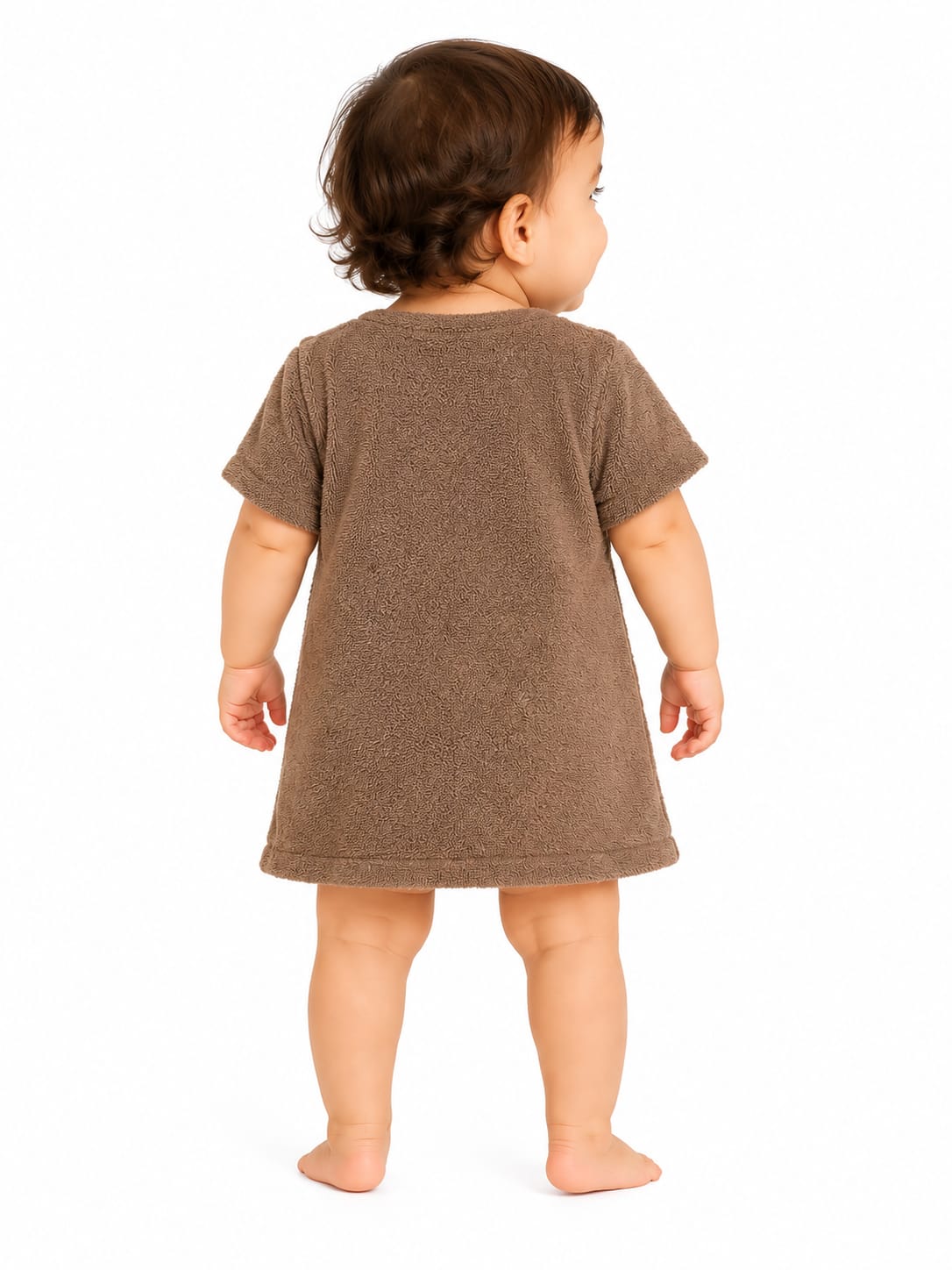 A toddler standing with their back to the camera, wearing a short-sleeve brown tunic dress against a plain white background.