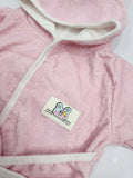 A close-up of a pink plush hooded towel robe with cream-colored trim and a small embroidered patch featuring a cartoon mouse and the text 'HABIBI GABONNI'.