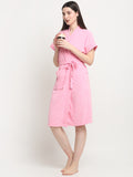 A woman standing and wearing a baby pink micro terry bathrobe and holding a cup