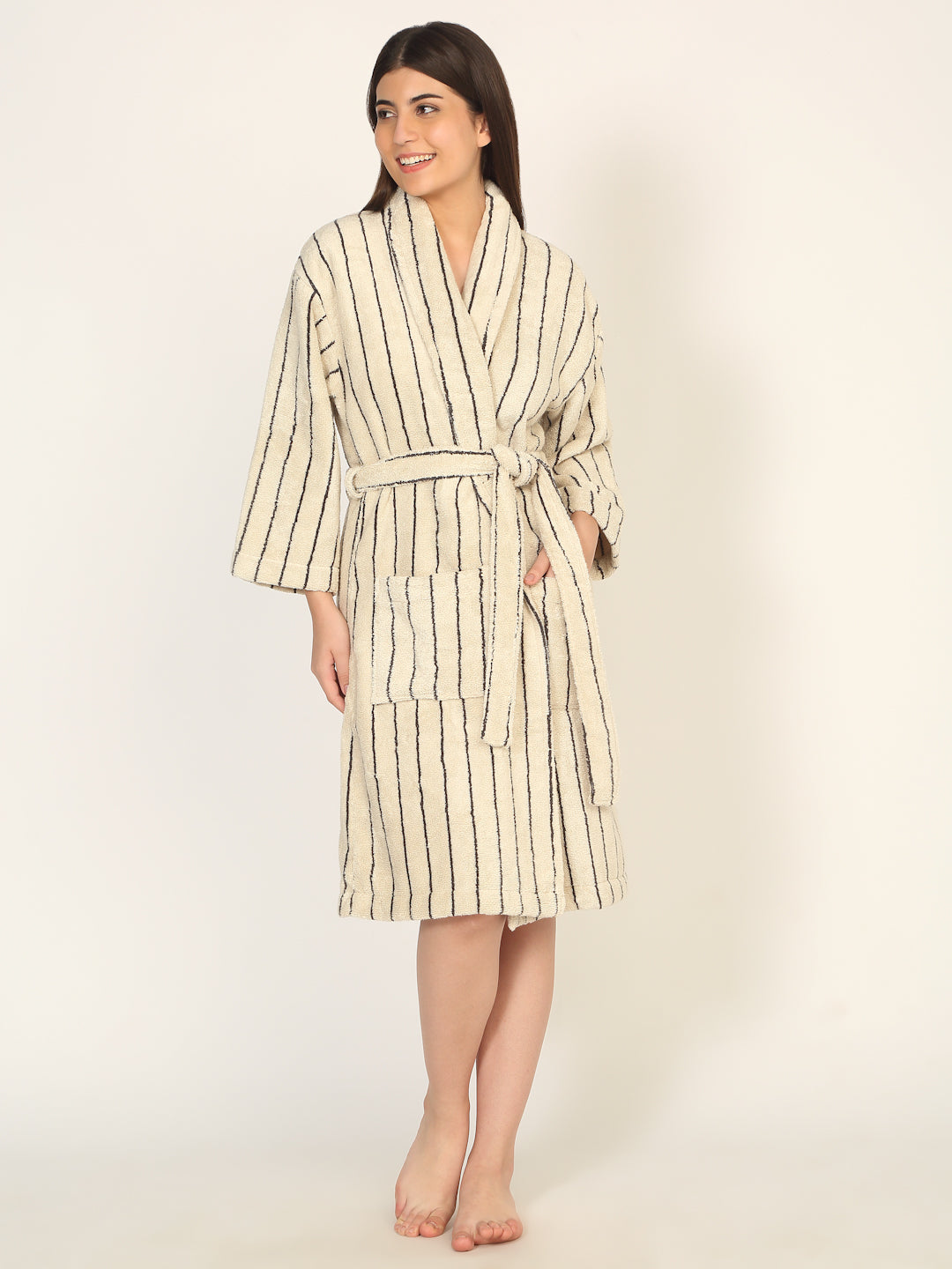 Woman wearing a striped bathrobe on a plain background