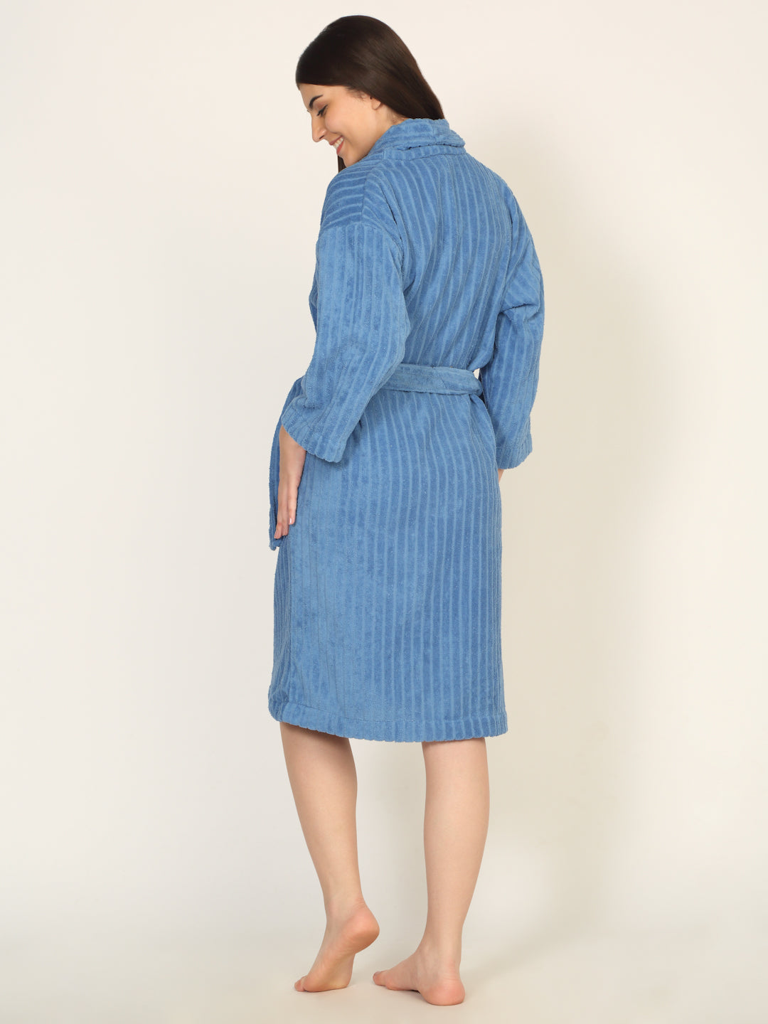 Woman wearing a blue textured bathrobe on a beige background