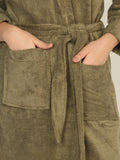 Person wearing a green robe with a belt, hands in pockets.