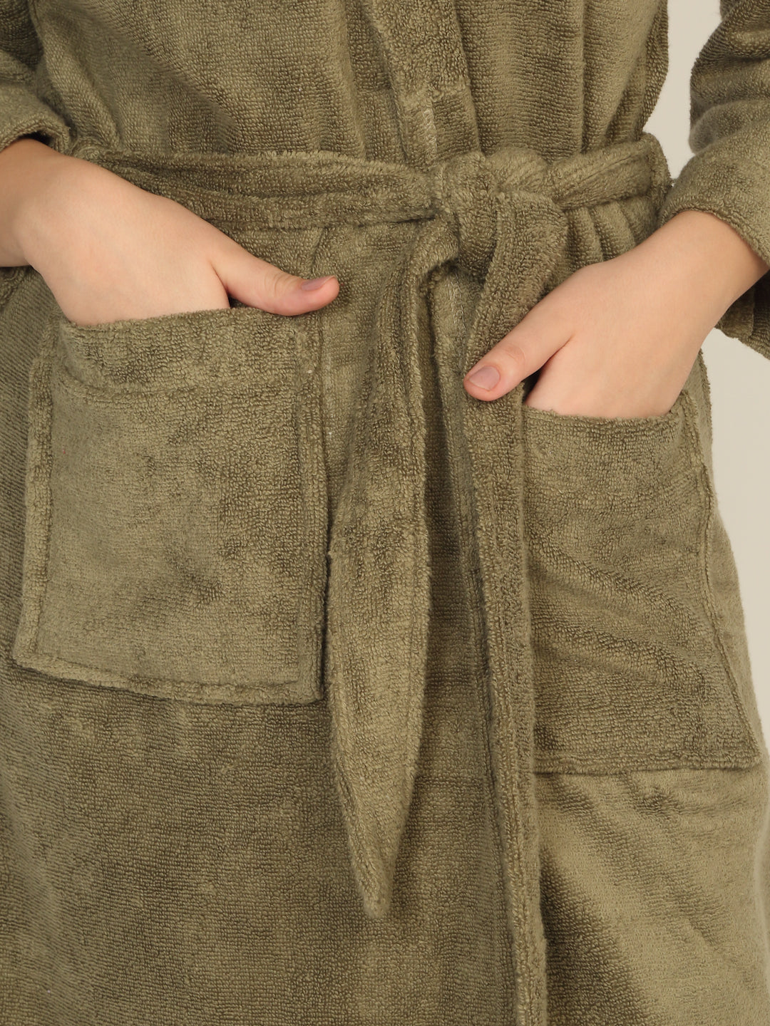 Person wearing a green robe with a belt, hands in pockets.