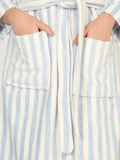 Close-up of a person wearing a blue and white striped robe with hands in pockets.