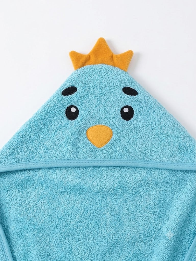 A light blue hooded towel shaped like a cartoon bird face, with embroidered black eyes, a yellow beak, and a small yellow crown on top, shown against a plain white background.