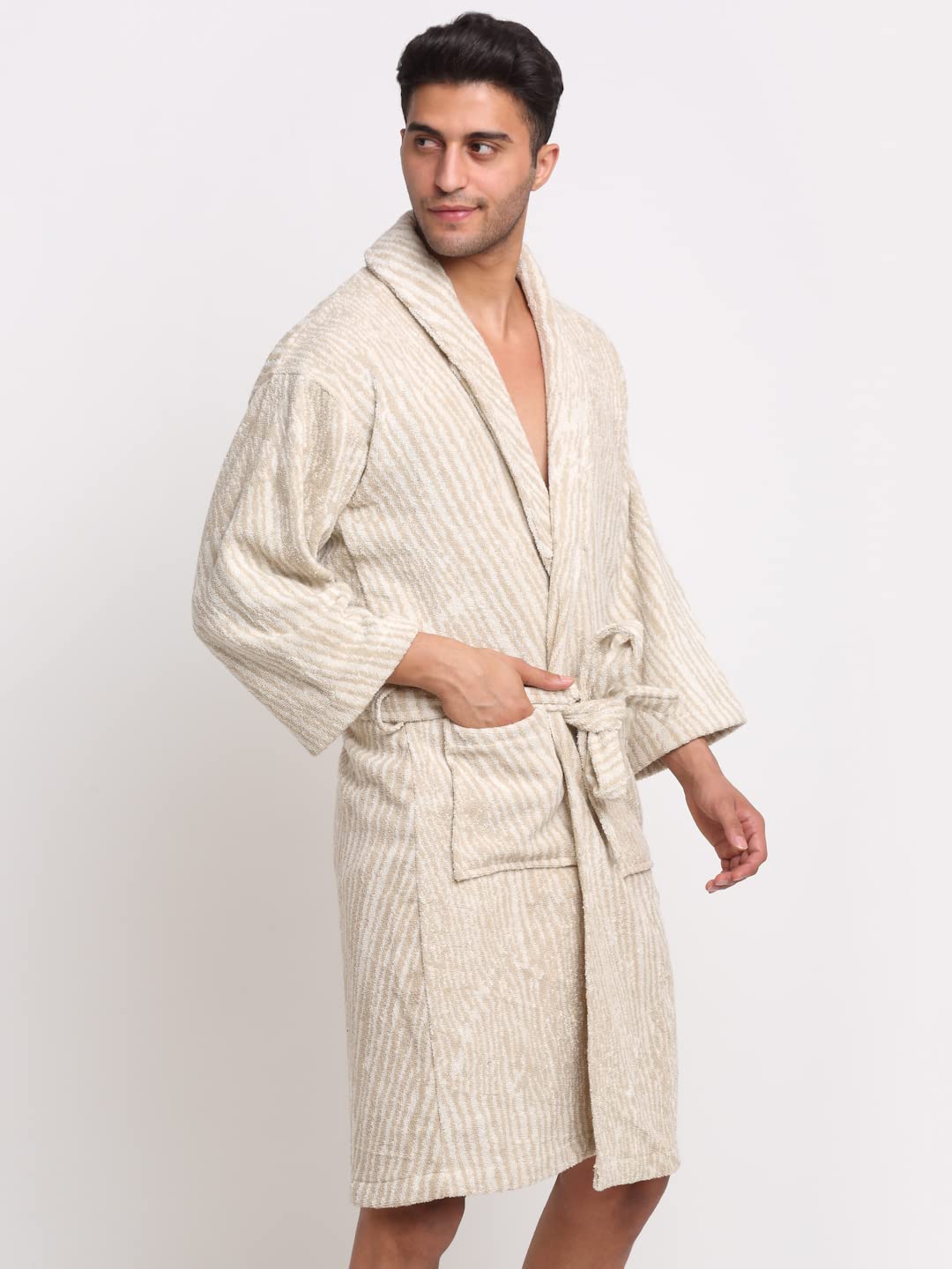 A man wearing a cream-colored textured bathrobe with vertical stripes, standing against a plain light gray background.