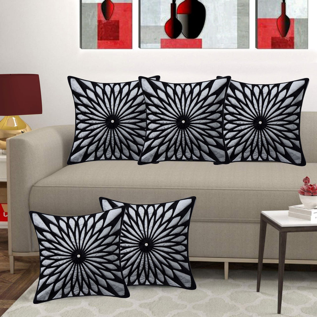 Black and white patterned pillows on a beige sofa with abstract art in the background.