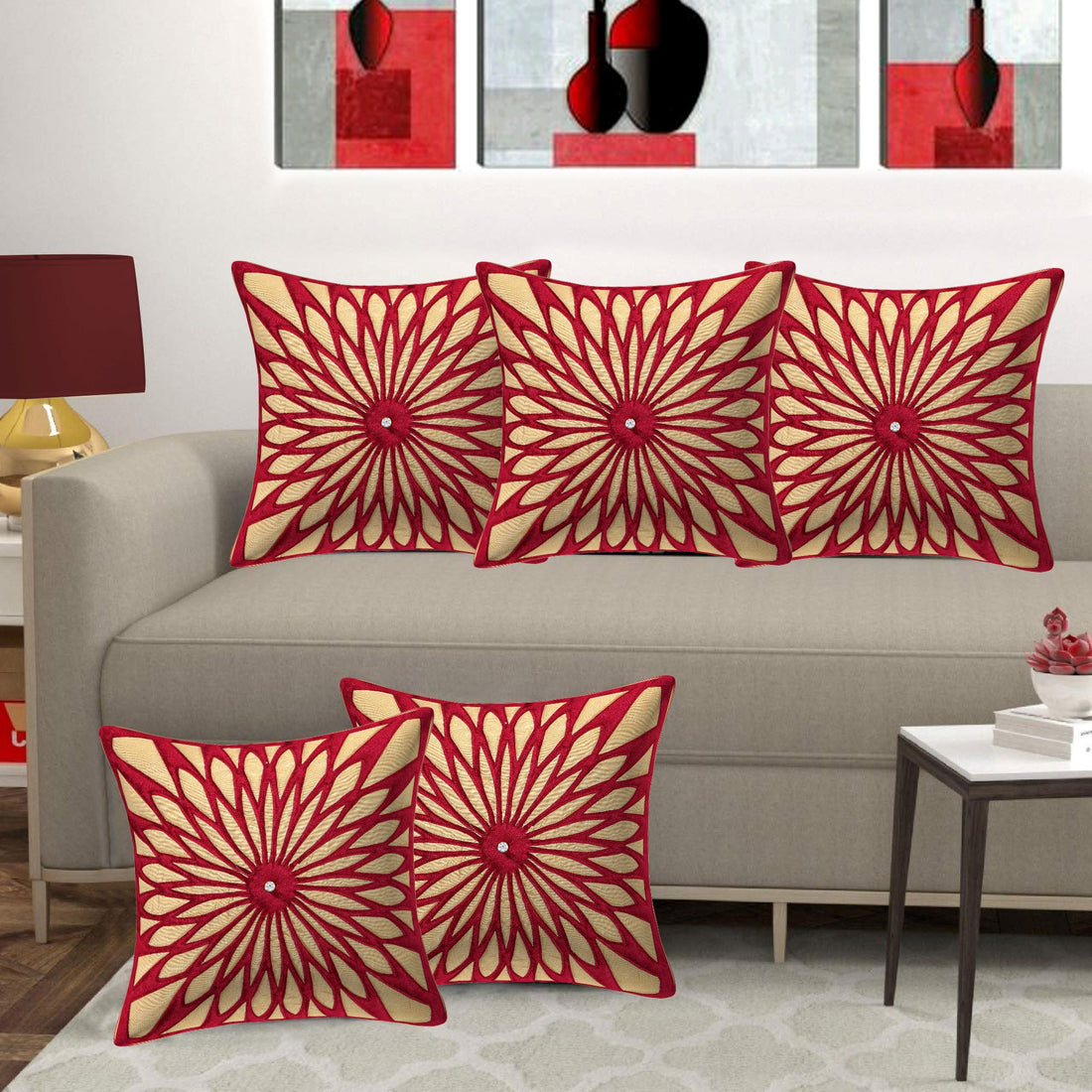 Red and beige patterned pillows on a gray sofa with abstract art in the background.