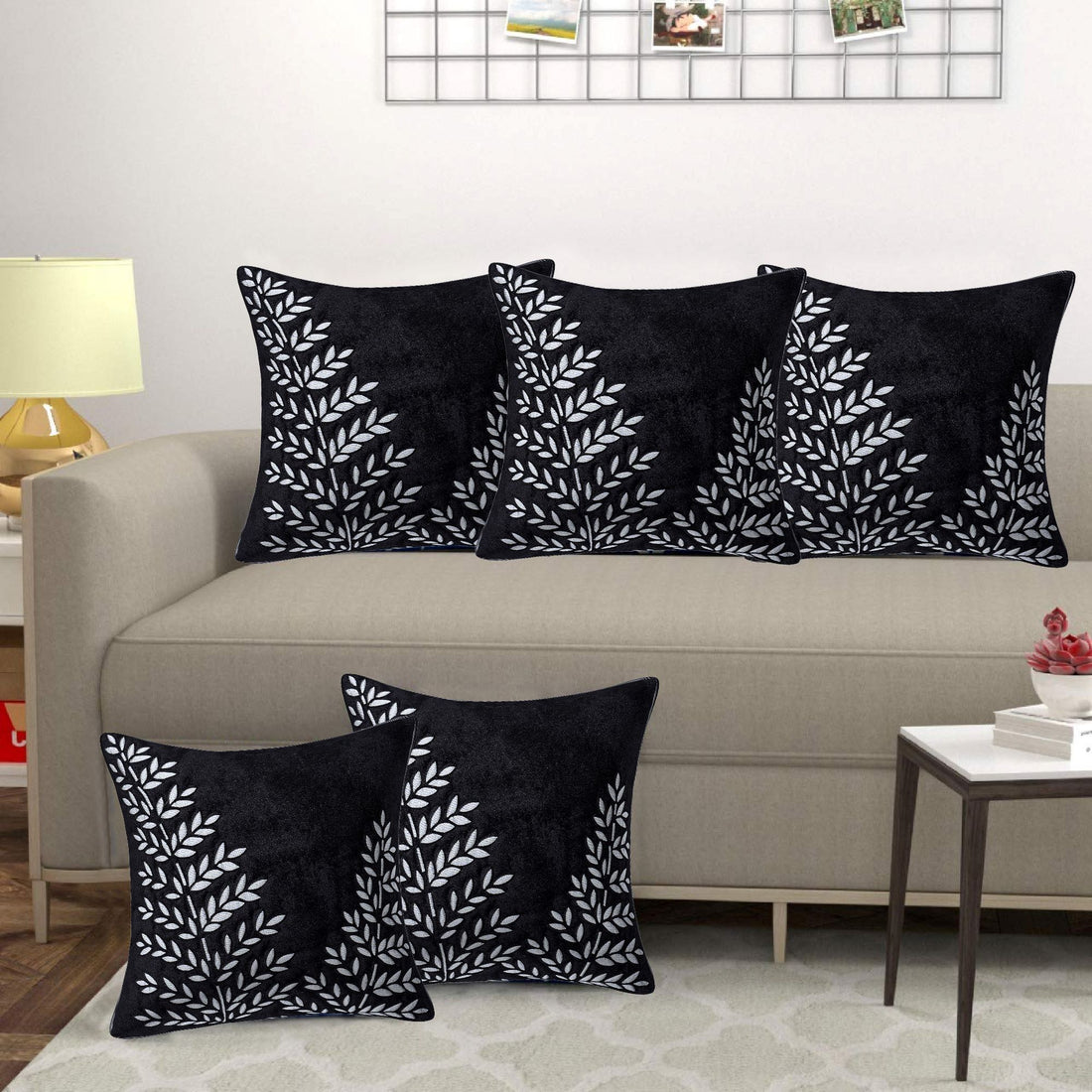 Black pillows with white leaf patterns on a beige sofa in a living room setting.