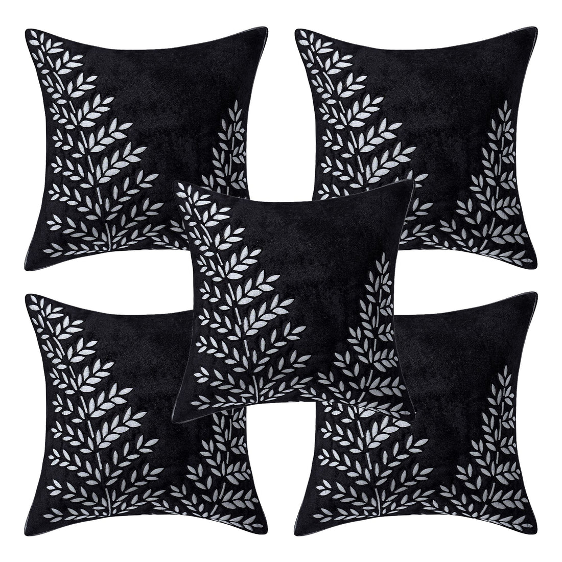 Black pillows with white leaf patterns on a beige sofa in a living room setting.
