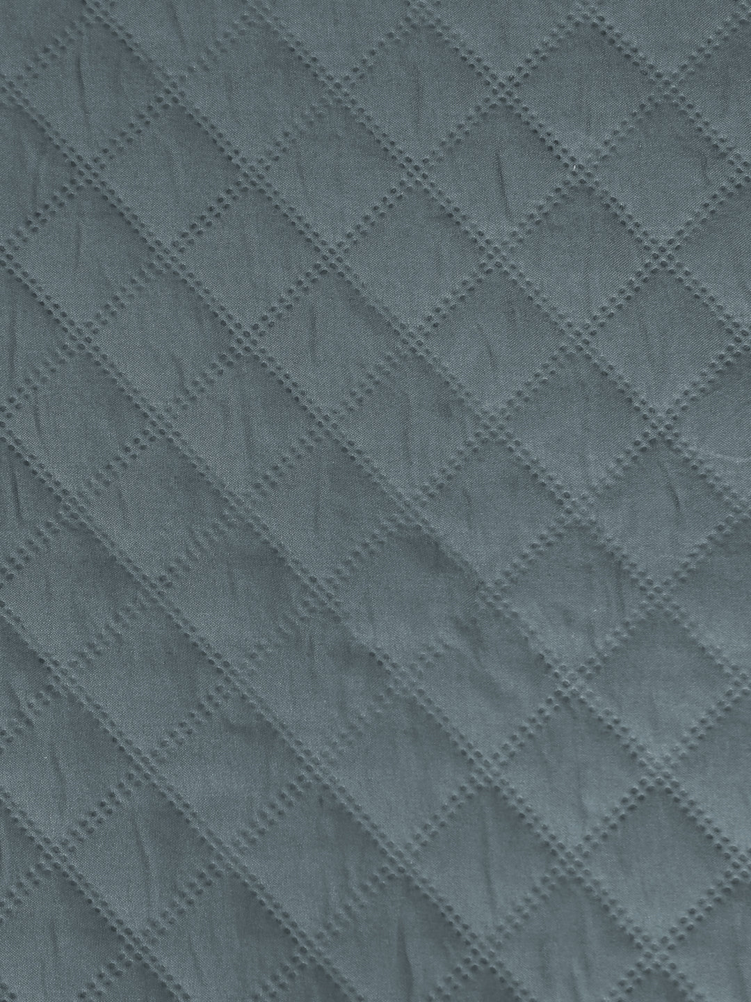 A close-up of a textured fabric with a repeating diamond quilted pattern in a muted slate blue-gray color.