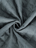A close-up of draped slate gray fabric with a subtle diamond quilted texture and stitched dot pattern, arranged in a spiral fold.