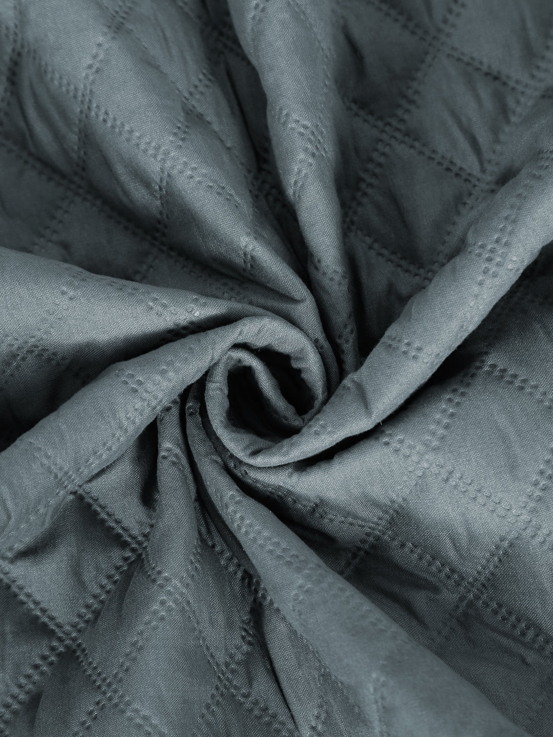 A close-up of draped slate gray fabric with a subtle diamond quilted texture and stitched dot pattern, arranged in a spiral fold.