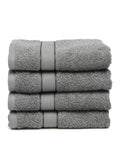 A set of grey Creeva brand hand towels stacked on a bathroom counter, with a wooden backdrop and a white bowl in the foreground.