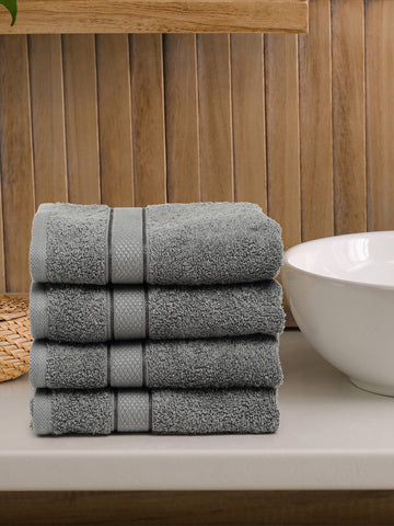 A set of grey Creeva brand hand towels stacked on a bathroom counter, with a wooden backdrop and a white bowl in the foreground.