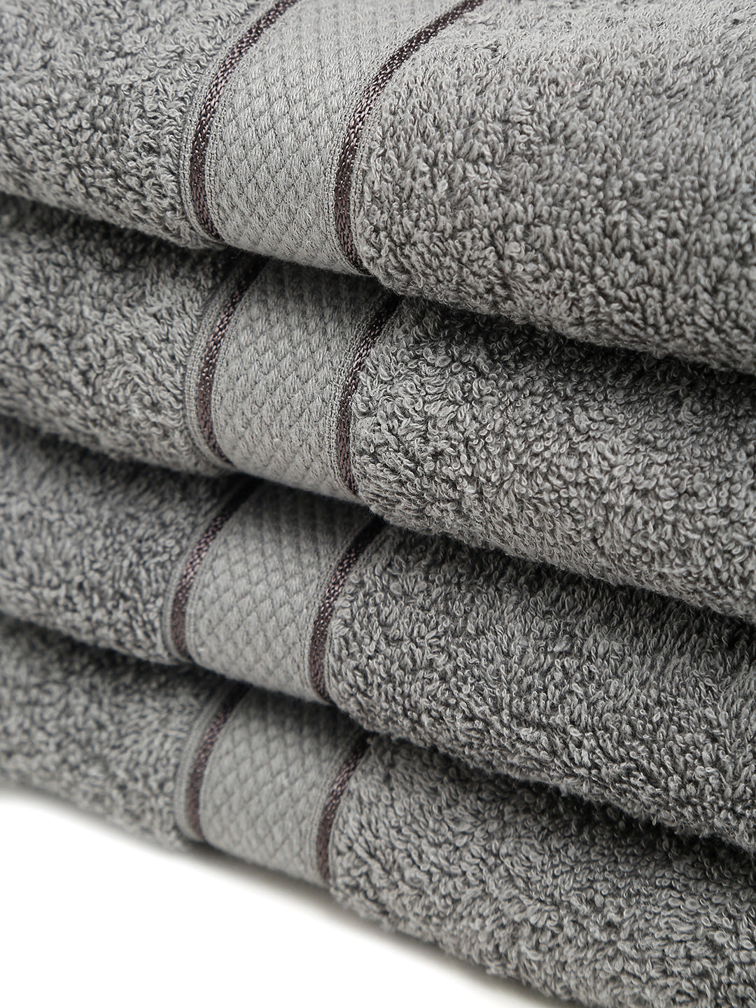 4 Stacked grey cotton towels with textured terry fabric and decorative stripe detailing.