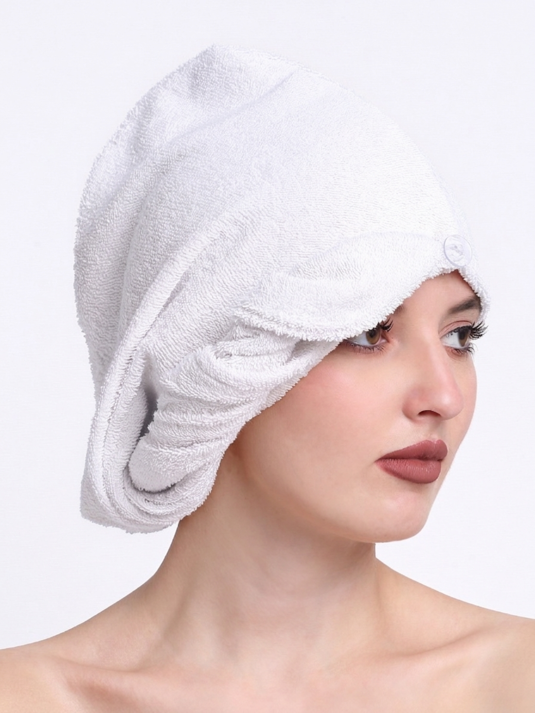 Woman wearing a white towel on her head against a plain background