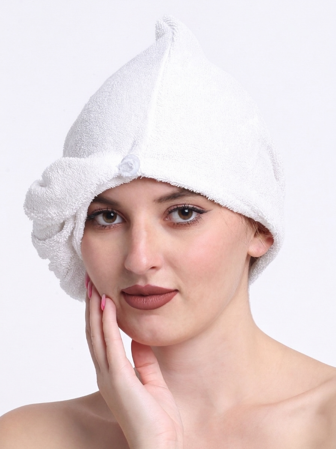 Woman wearing a white towel on her head against a plain background