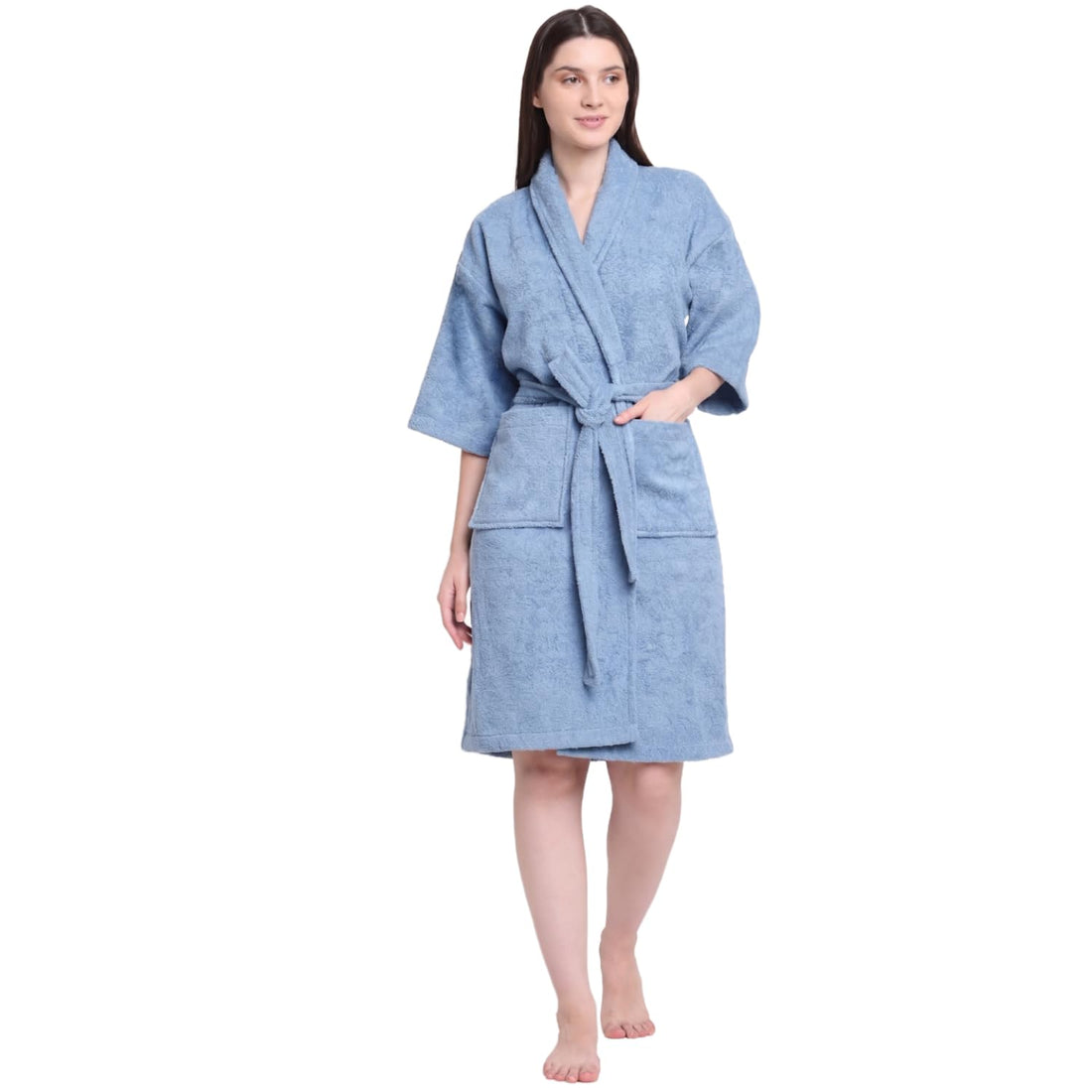 A woman modeling a light blue textured bathrobe with a tie waist and front pockets, standing against a plain white background.