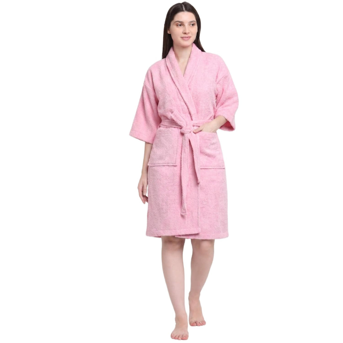 A woman modeling a pink terry cloth bathrobe with a shawl collar, three-quarter sleeves, a self-tie belt, and front patch pockets, set against a plain white background.