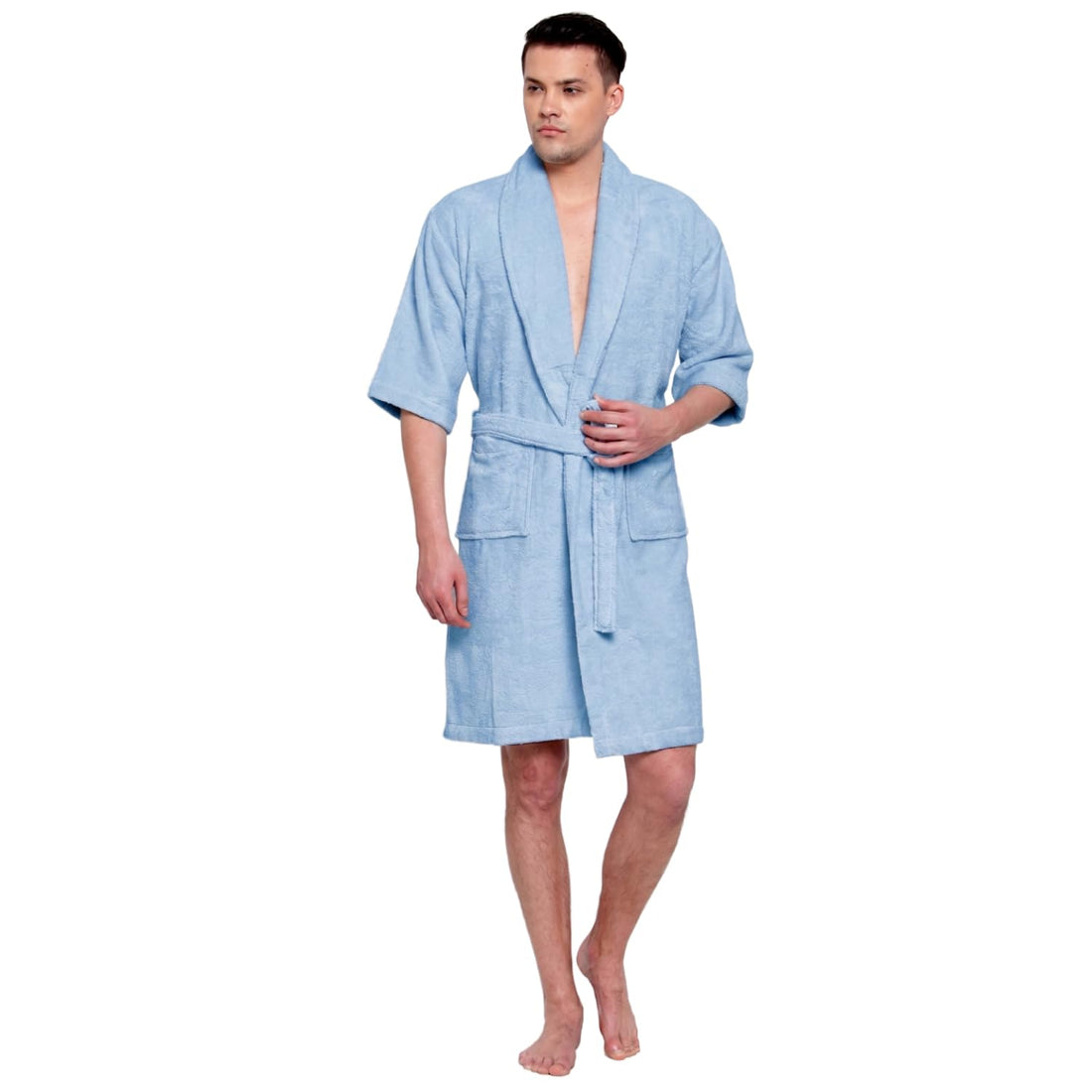 A man modeling a light blue terry cloth bathrobe with a shawl collar, waist tie, and front patch pockets against a plain white background.