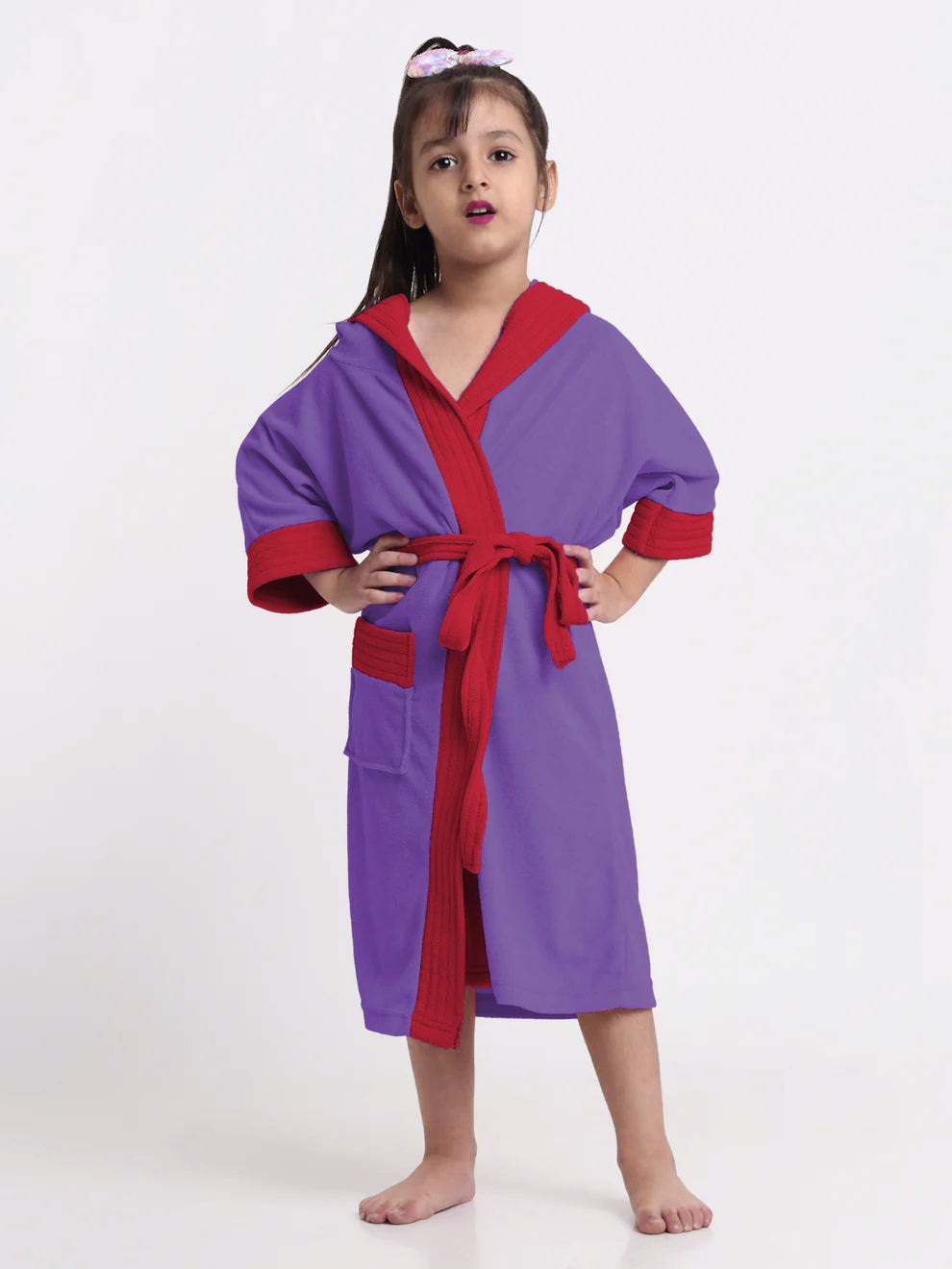 Child wearing an indigo and red robe with a small plant on a white table in the background