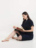 A woman sitting and wearing a navy-blue micro terry bathrobe and holding a book
