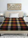 A bed dressed in a multicolor tartan plaid sheet or duvet, styled in a modern bedroom setting with a beige headboard, white pillow, bedside tables, lamps, and a framed horse painting on the wall.