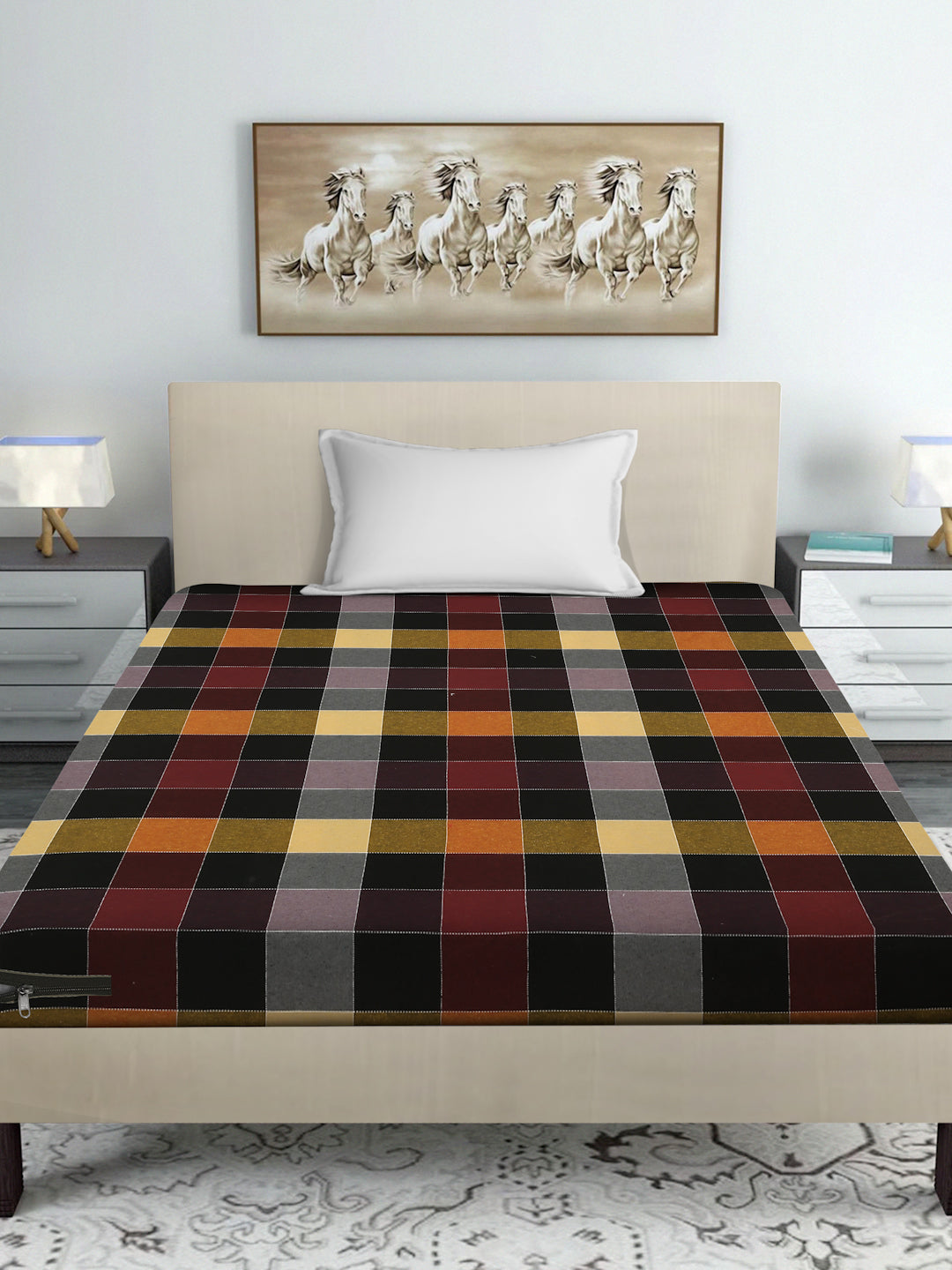 A bed dressed in a multicolor tartan plaid sheet or duvet, styled in a modern bedroom setting with a beige headboard, white pillow, bedside tables, lamps, and a framed horse painting on the wall.