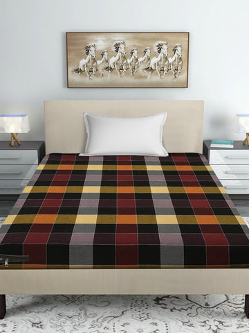 A bed dressed in a multicolor tartan plaid sheet or duvet, styled in a modern bedroom setting with a beige headboard, white pillow, bedside tables, lamps, and a framed horse painting on the wall.