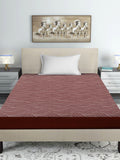 Bed with red and white patterned bedspread, beige headboard, and decorative painting on wall.