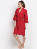 A woman modeling a red bathrobe with three-quarter sleeves and a self-tie belt, standing against a plain white studio background.