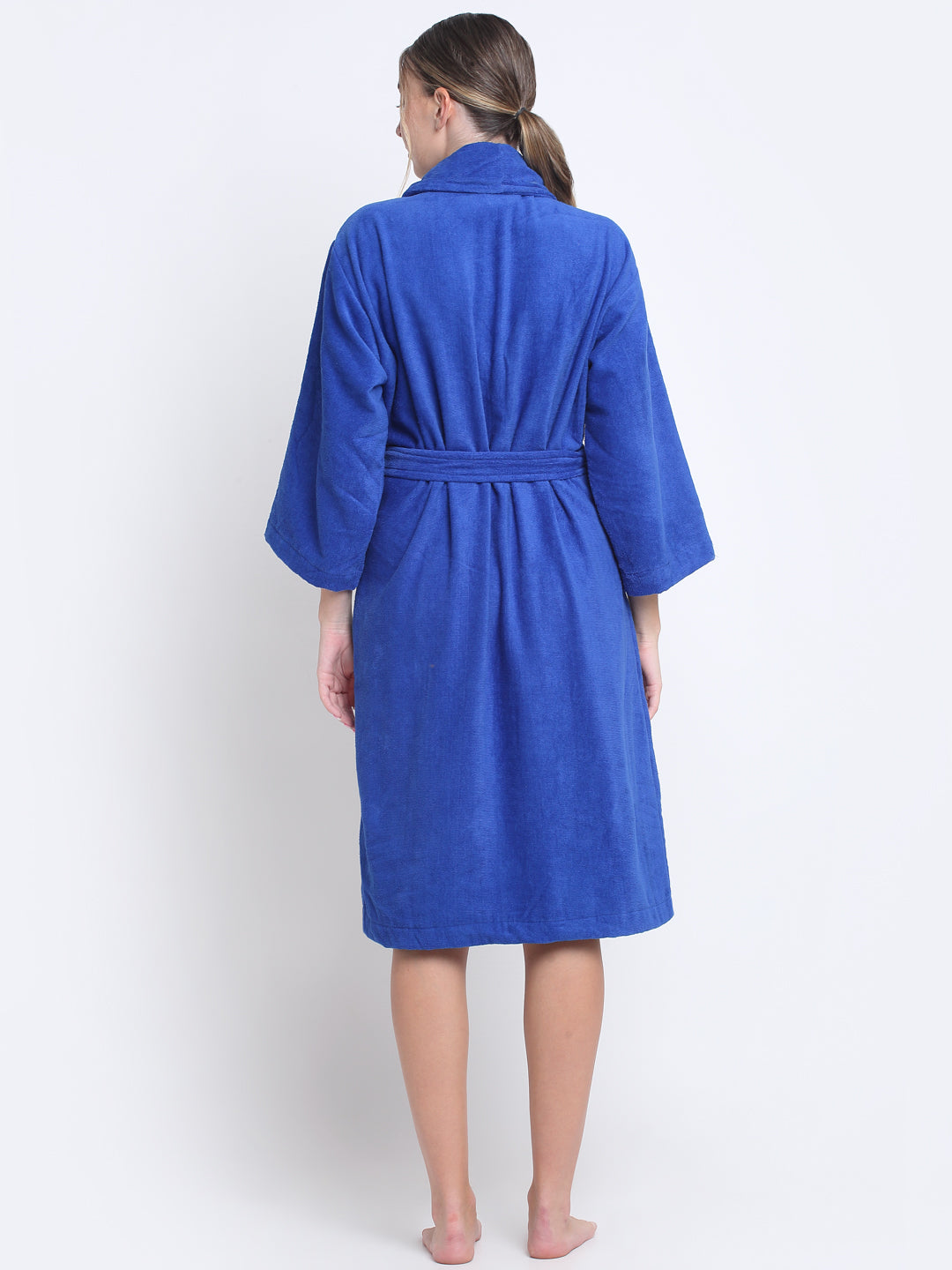 Back view of a woman wearing a royal blue bathrobe with a waist belt