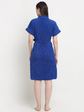 Back view of a woman wearing a royal blue micro terry bathrobe with a tie belt