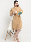 Woman standing side by chair wearing a sky blue micro terry bathrobe and holding a book and cup