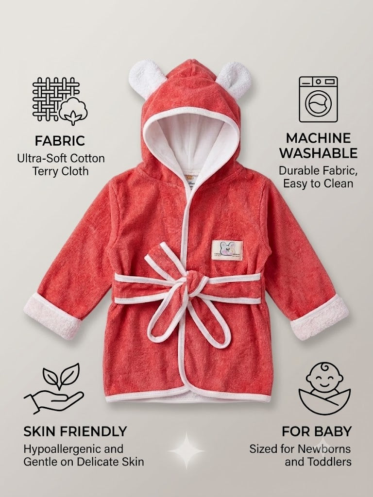 A coral red hooded baby bathrobe with white trim and ear-like hood details, shown on a light beige background with feature callouts for fabric, machine washability, skin friendliness, and baby suitability.