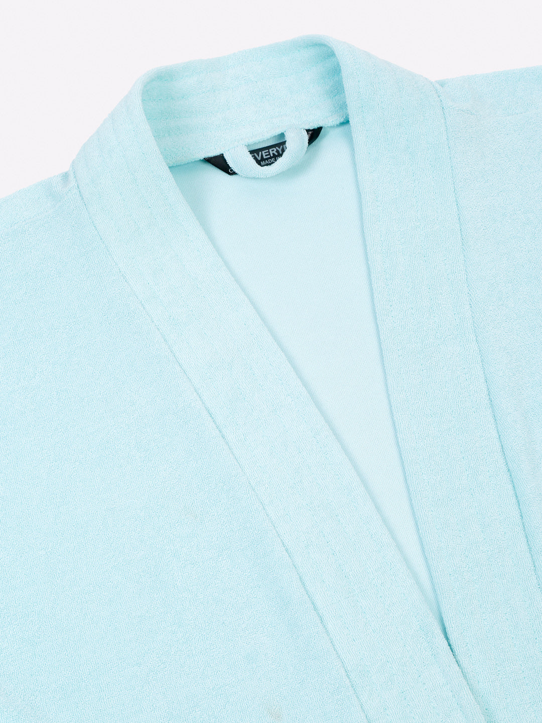 Close-up of a sky blue micro terry bathrobe showing the collar and fabric texture