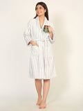 Woman wearing a white and gray striped robe holding a mug on a beige background