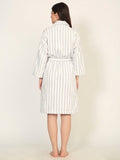 Woman wearing a white and gray striped robe on a plain background