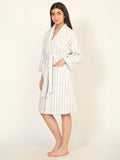 Woman wearing a white striped robe on a plain background