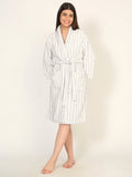 Woman wearing a white and gray striped robe on a plain background