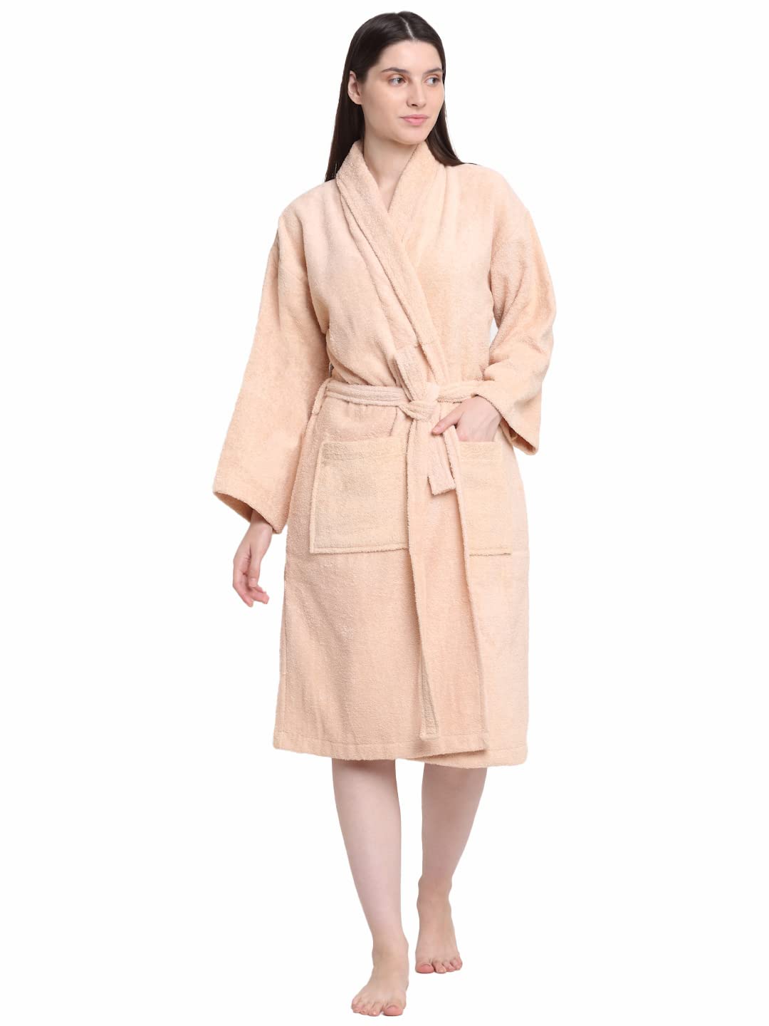A woman modeling a light peach-colored terry cloth bathrobe with a matching tie belt, standing against a plain white background.