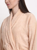 A close-up of a woman wearing a plush, light peach-beige terry cloth bathrobe against a plain white background.