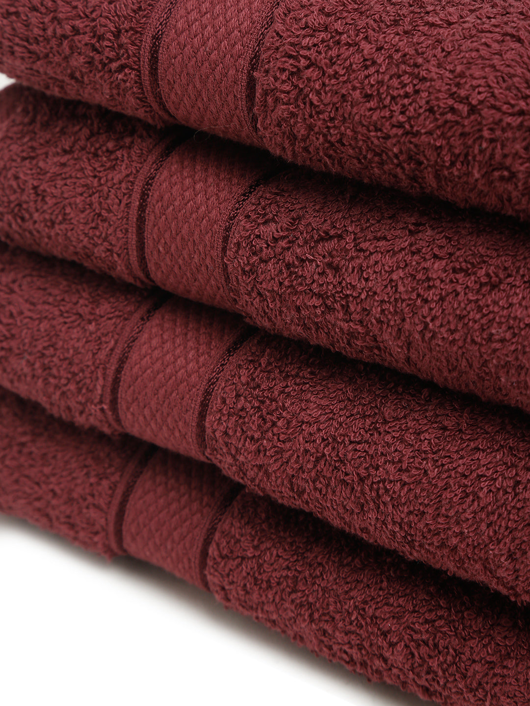 4 Stacked wine cotton towels with textured terry fabric and decorative stripe detailing.