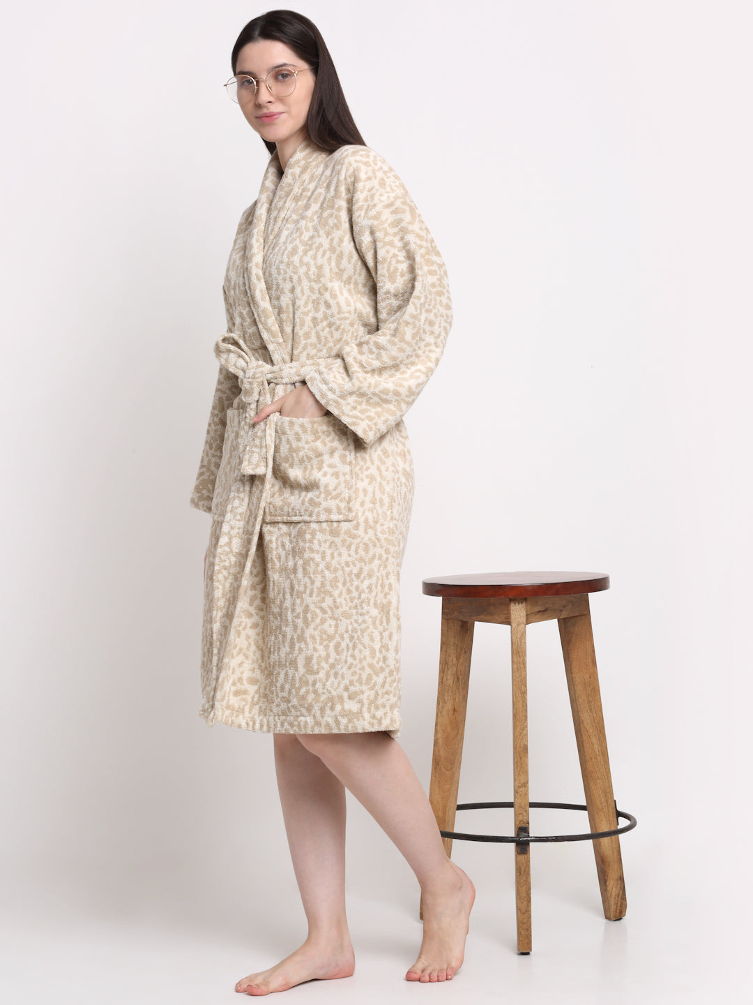 A person standing, wearing a cream-colored bathrobe with a rust-dotted pattern.