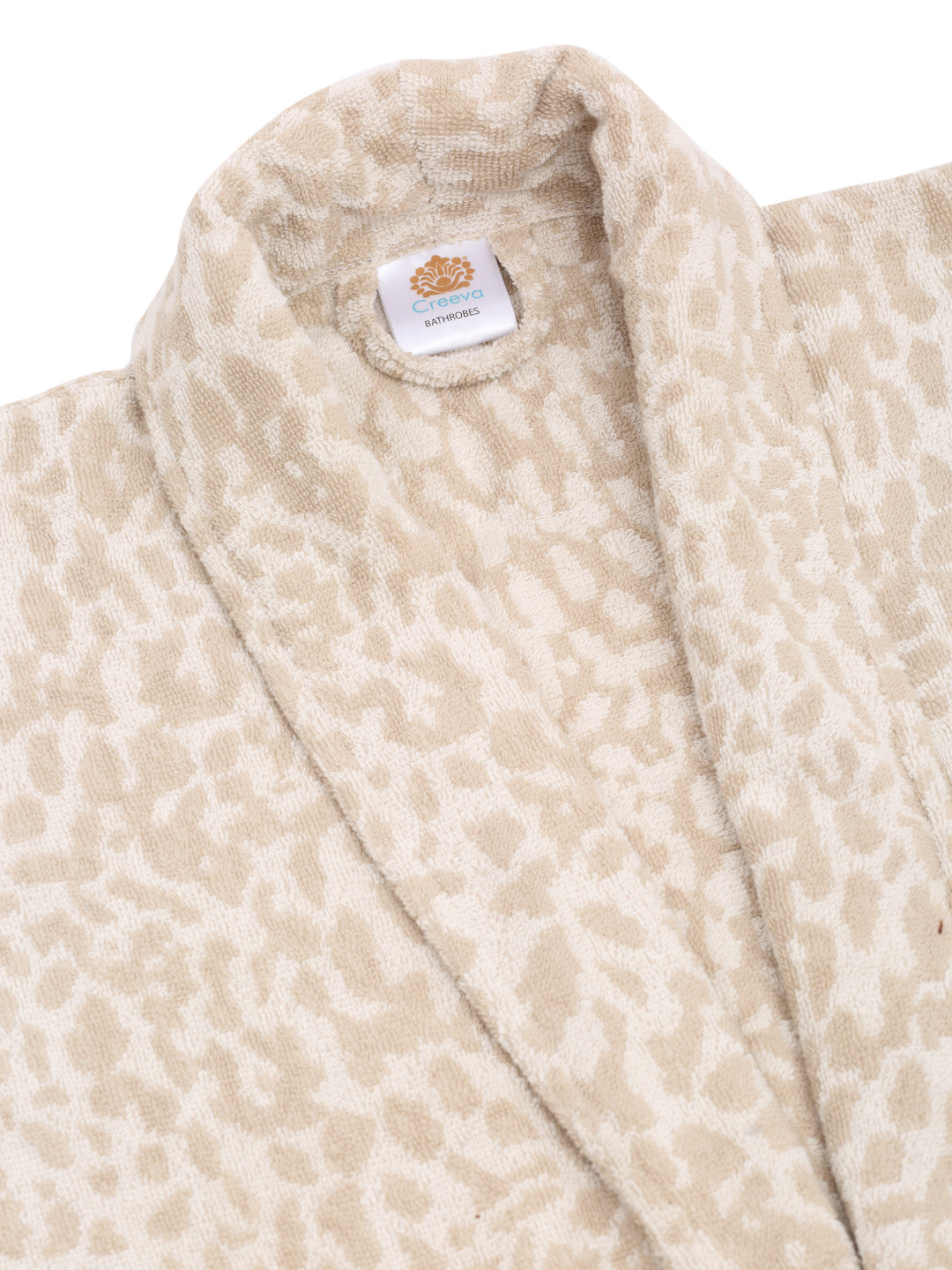 Close-up of a cream and rust cotton bathrobe showing the shawl collar, soft terry texture, and CREEVA label