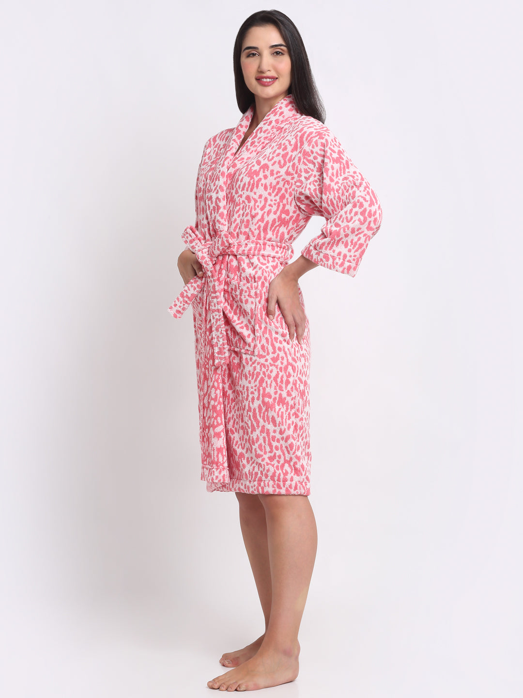A woman sitting on a stool wearing a pink leopard print bathrobe.
