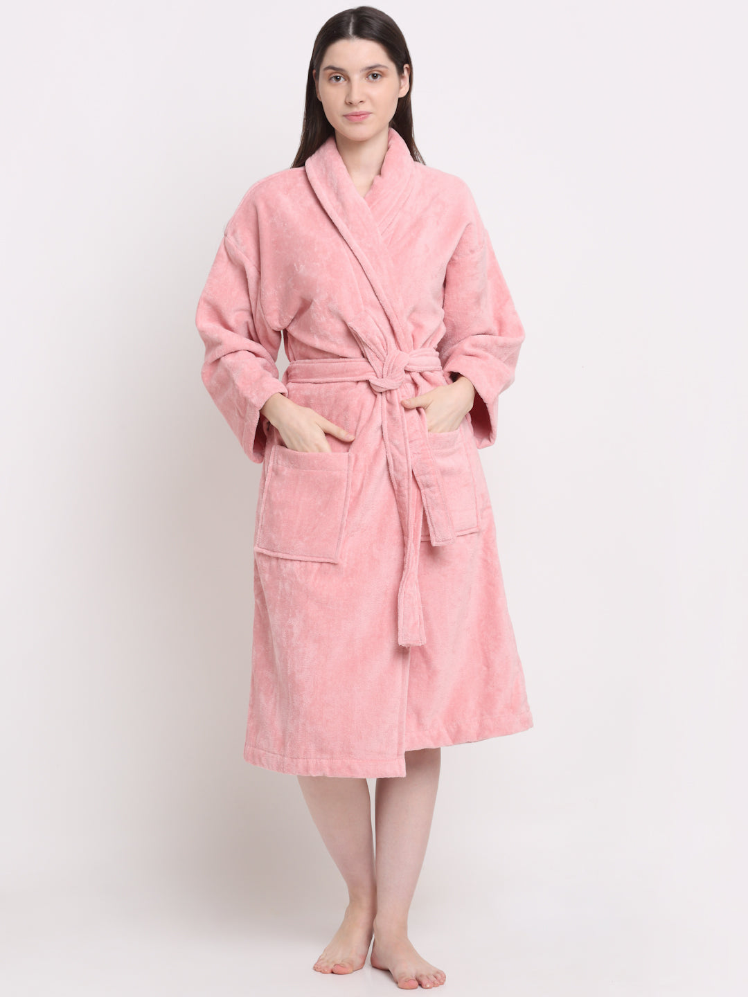 A person wearing a pink unisex cotton bathrobe and standing 